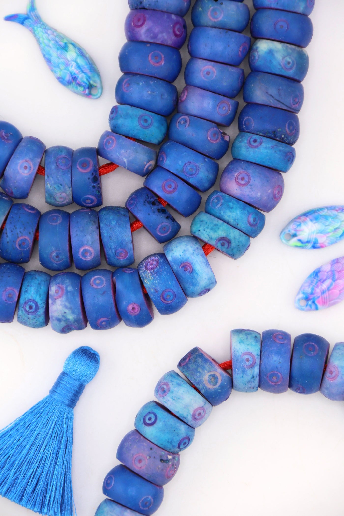 Close-up of blue donut-shaped carved bone beads with whimsical bullseye pattern, handmade and ethically sourced.