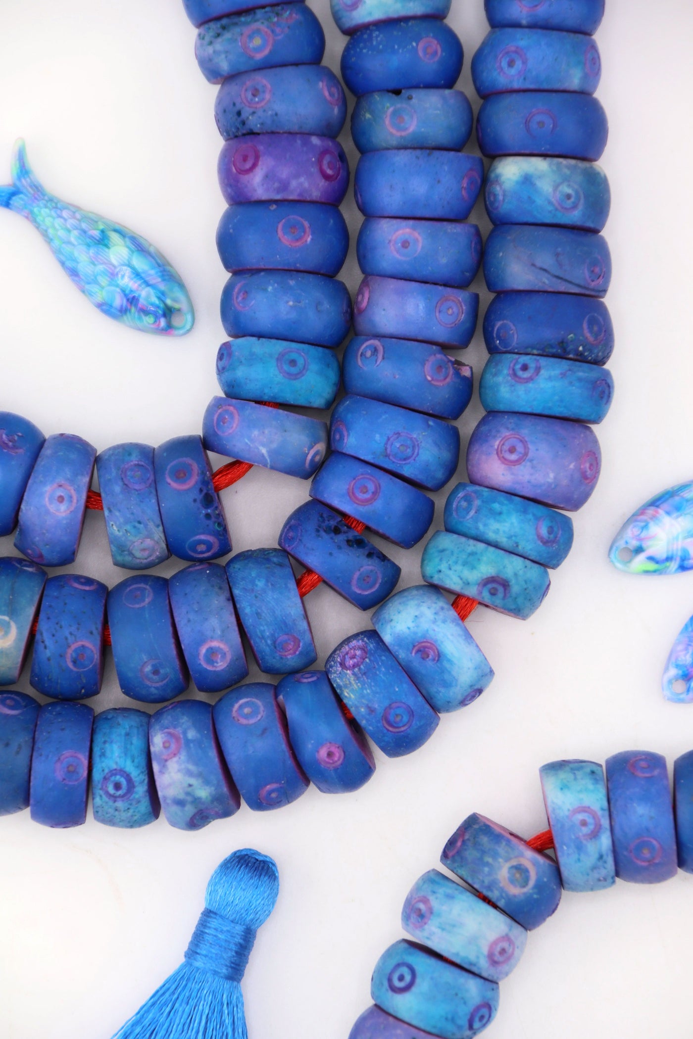 Chunky blue carved bone beads, 14x7mm donuts with large holes, styled in layered strands.