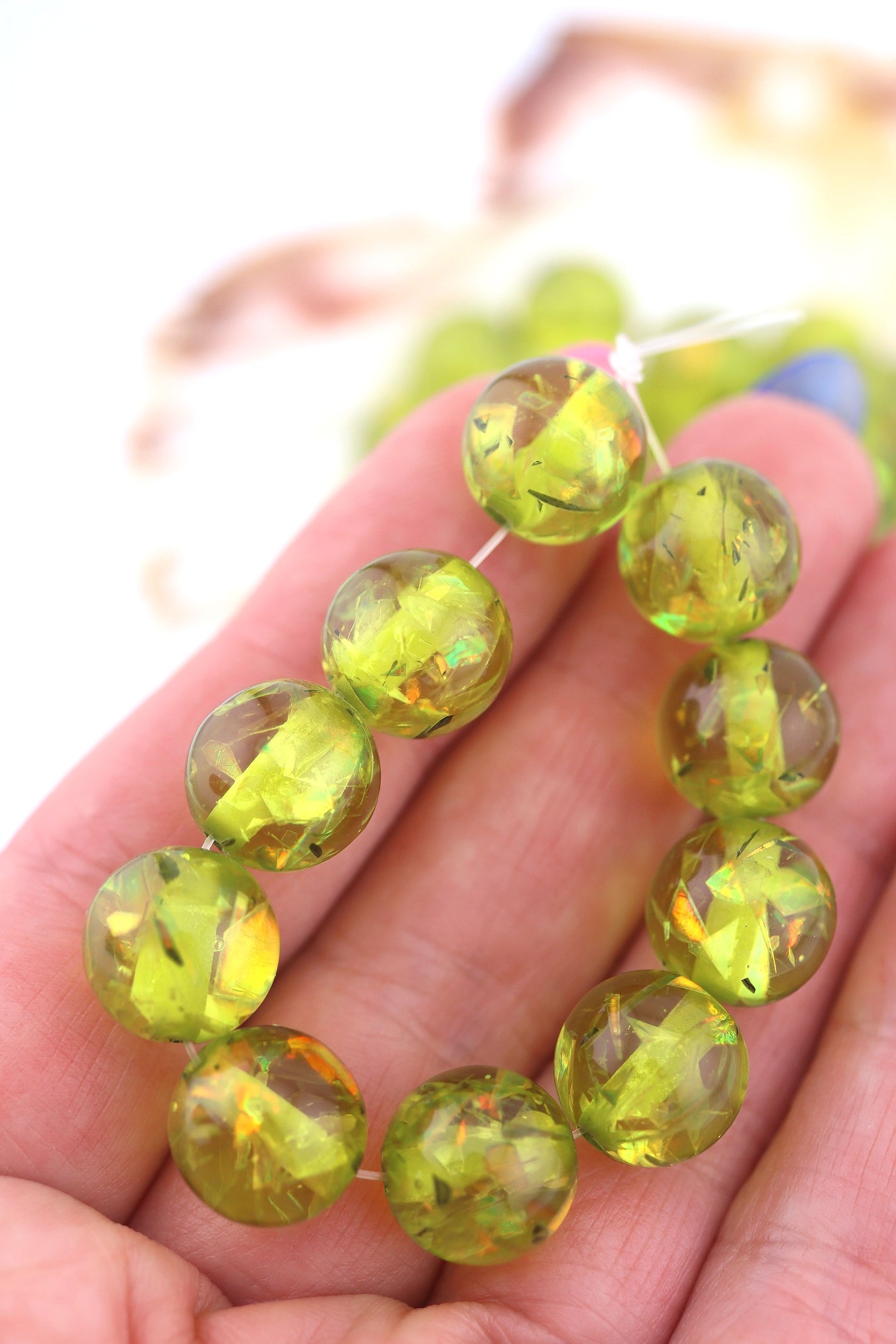 Close-up of a hand holding a bracelet with green beads against a blurred background