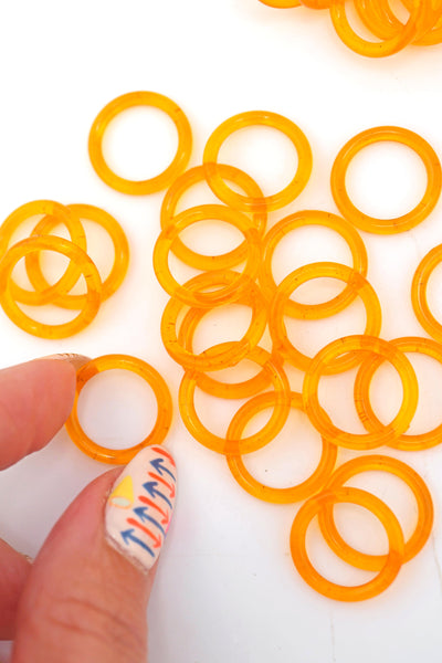 Fingers reach for a translucent orange resin ring for jewelry making