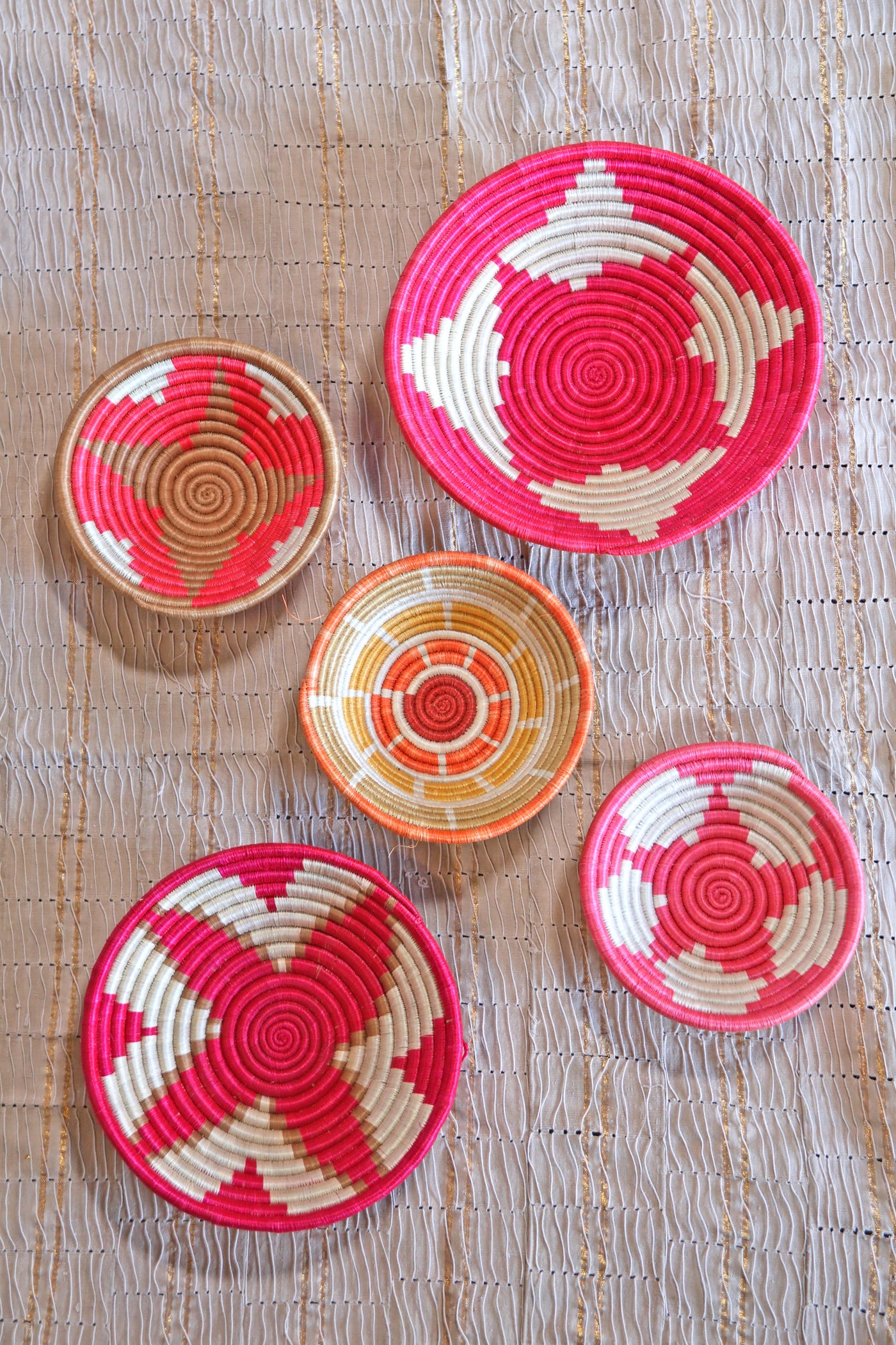 Petra African Basket Collection, Fuchsia Pink, from Rwanda, Set of 5 baskets placed on a woven khaki