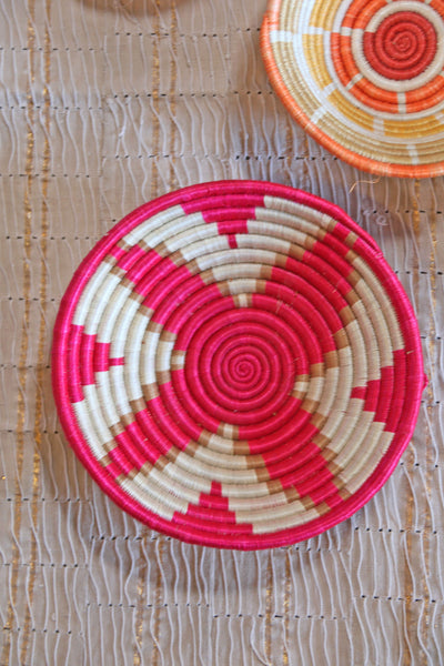 Petra African Basket Collection, Fuchsia Pink basket placed on a woven khaki African textile