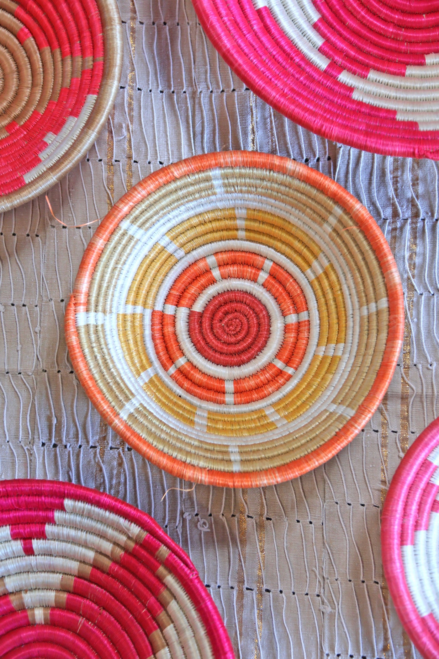 Petra African Basket Collection, Fuchsia Pink basket placed on a woven khaki African textile