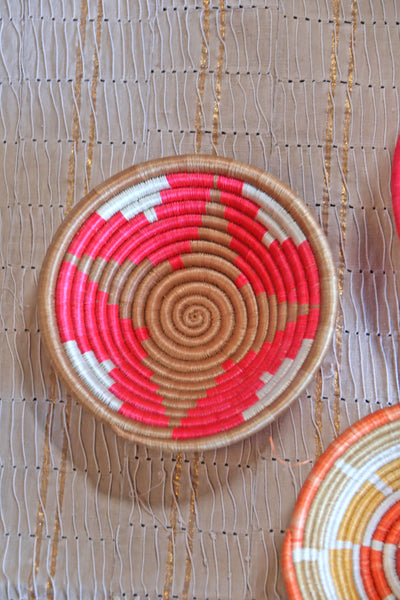 Petra African Basket Collection, Fuchsia Pink basket placed on a woven khaki African textile