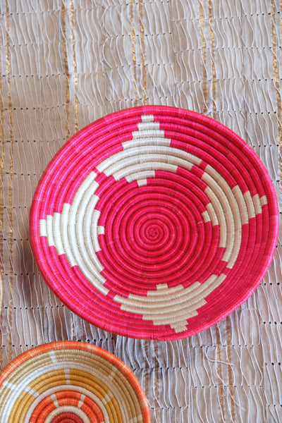 Petra African Basket Collection, Fuchsia Pink basket placed on a woven khaki African textile