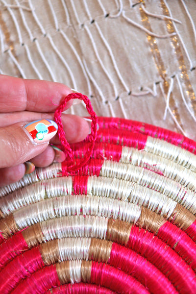 Petra African Basket Collection, Fuchsia Pink basket placed on a woven khaki African textile