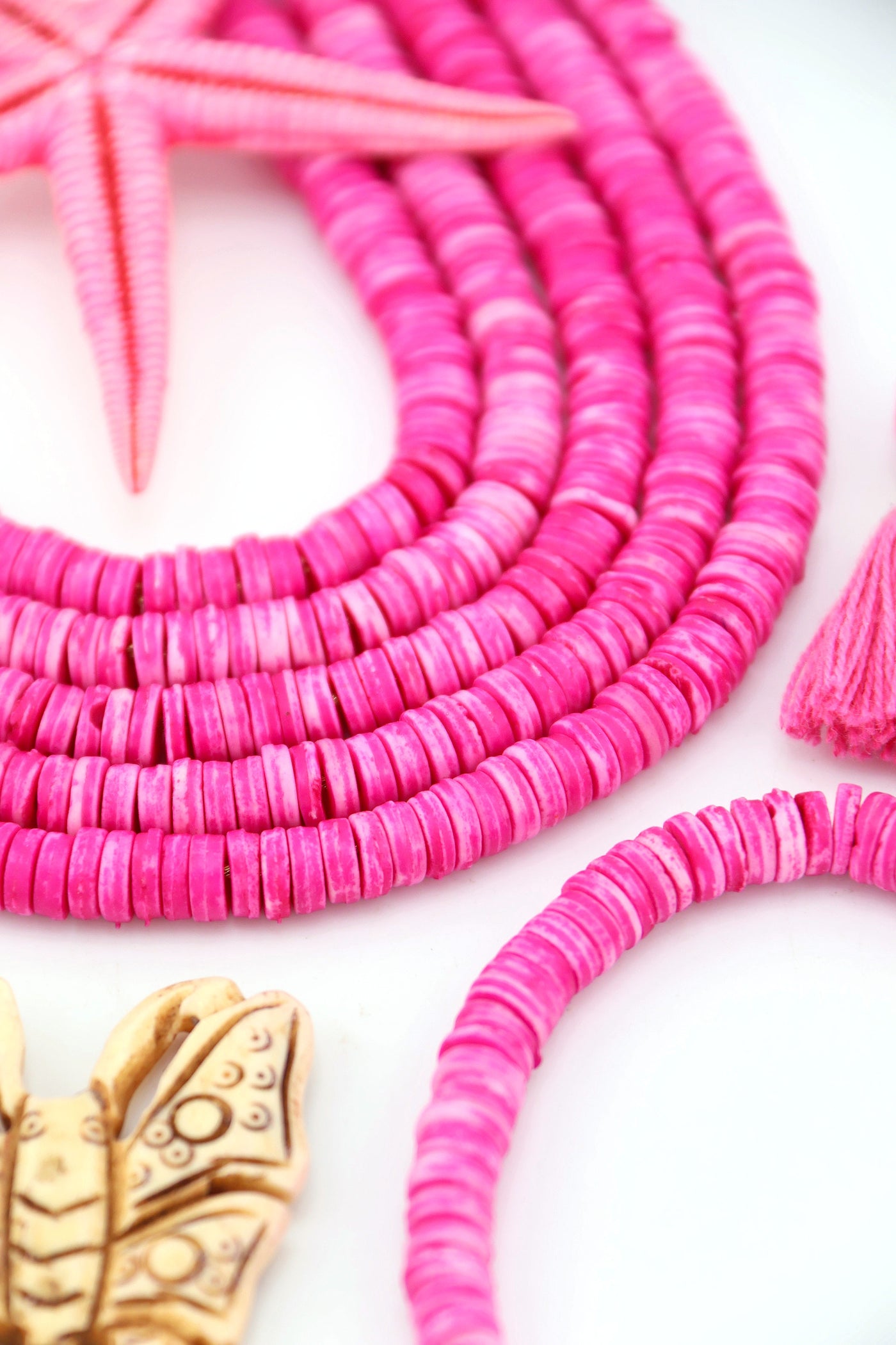 Bright Pink Bone Heishi Disc Beads, 7mm, 100+ beads  draped in an arc with a butterfly pendant and a starfish