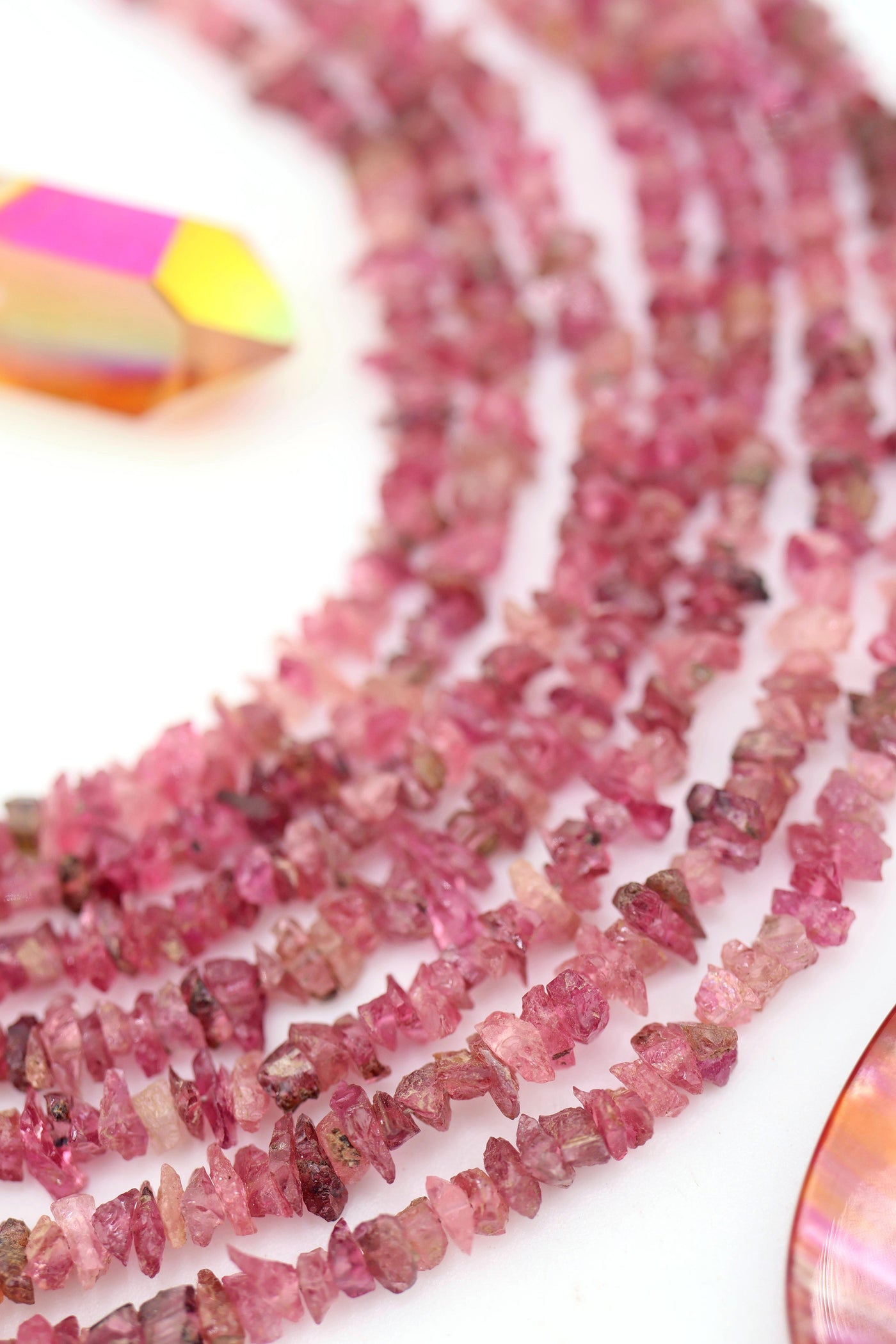 Rows of pink tourmaline microchip beads with light reflecting off their raw, natural texture.