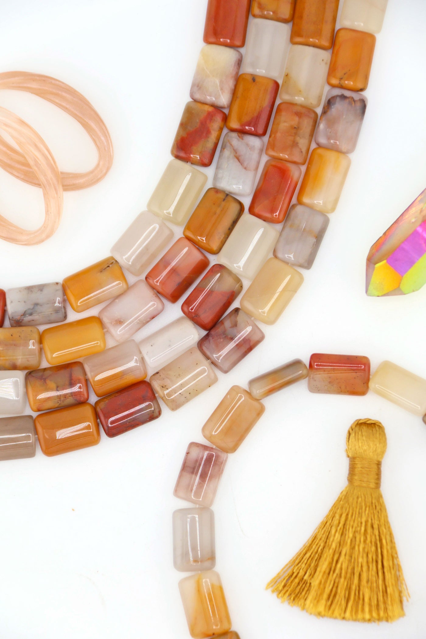 Close-up of polished Sansha Jasper puffed rectangle beads in earthy gold, cream, and terracotta tones, strung in neat rows