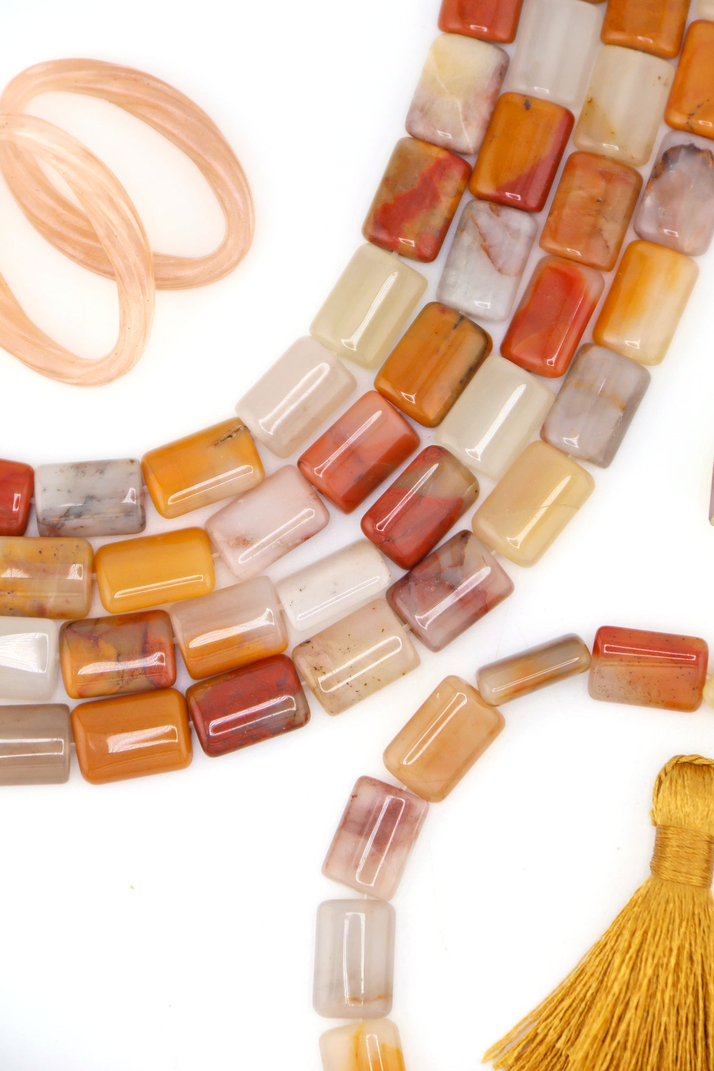 Flatlay of genuine Sansha Jasper gemstone beads with warm natural colors and glossy rectangular shapes for jewelry making.