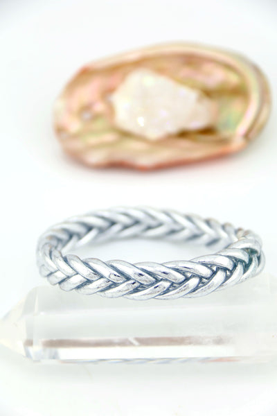 Silver bracelet with braided design on a white background