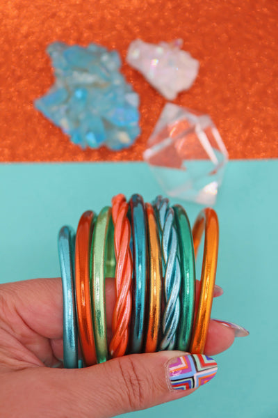 Orange, Aqua, Mint Green metallic bracelet stack, held in a hand, Showgirl Era jewelry
