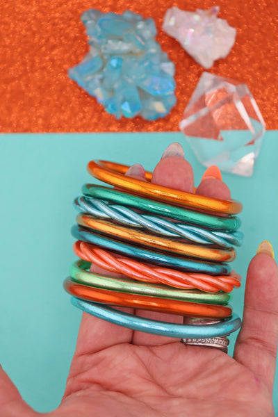 Orange, Aqua, Mint Green metallic bracelet stack, held in a hand, Showgirl Era jewelry