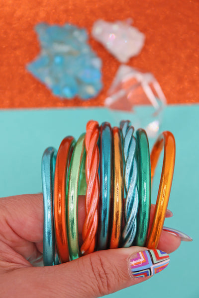 Orange, Aqua, Mint Green metallic bracelet stack, held in a hand, Showgirl Era jewelry