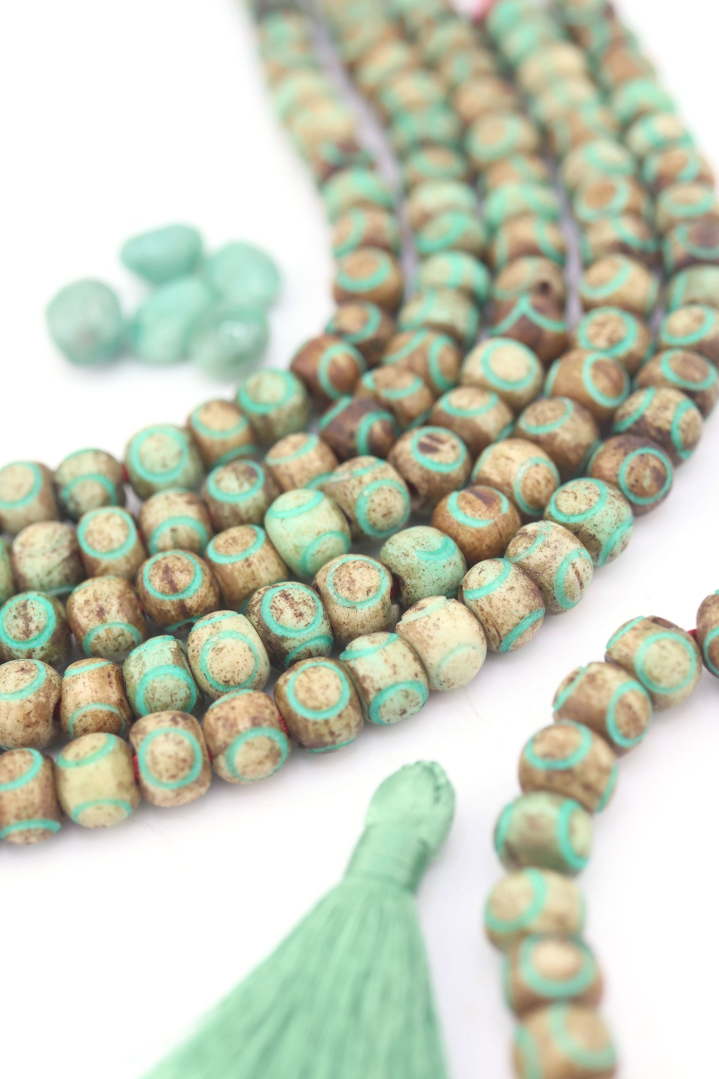 Earthy round carved bone beads in brown and turquoise on string