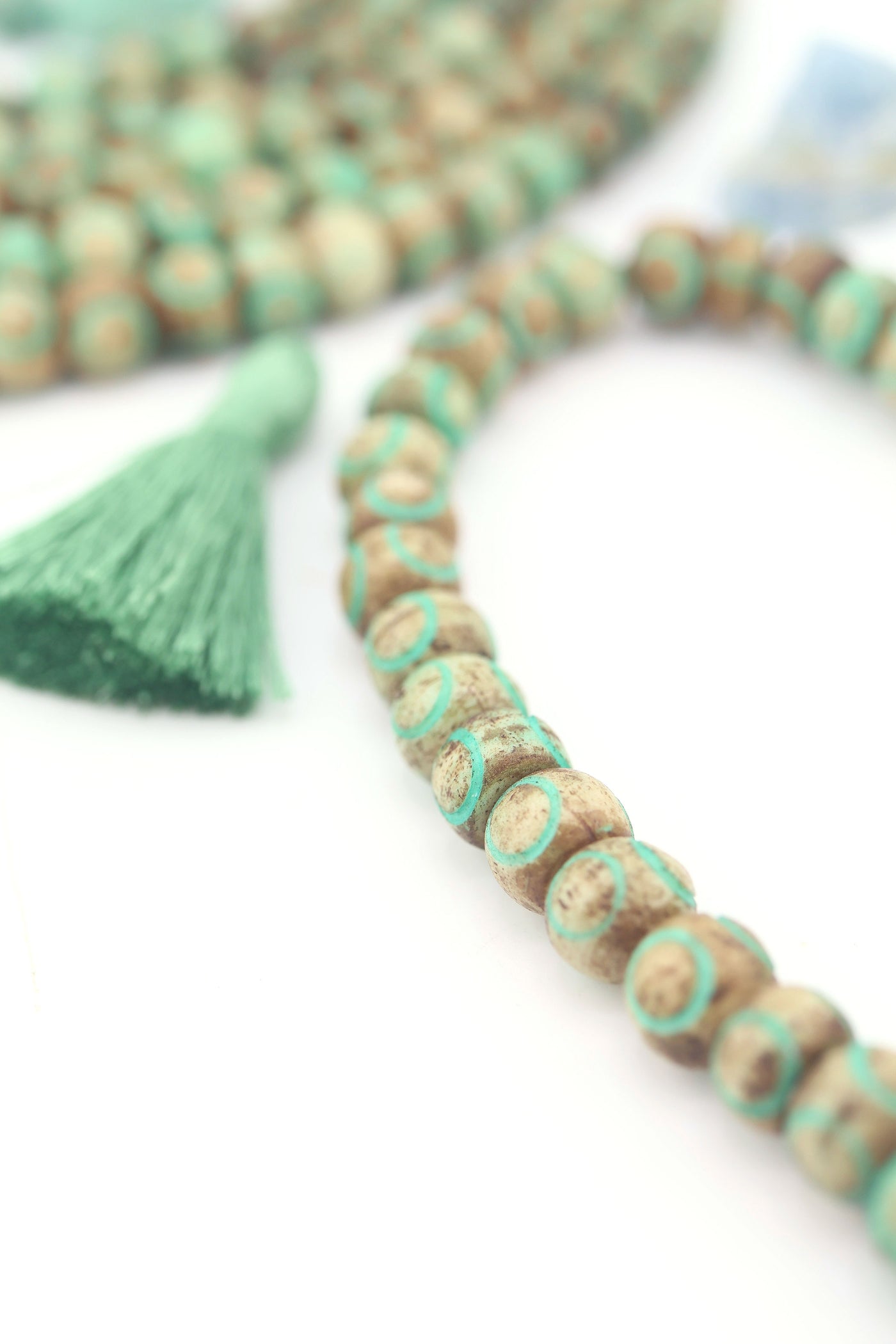 Close-up of rustic brown bone beads with turquoise circle patterns on strand