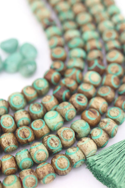 Earthy round carved bone beads in brown and turquoise on string