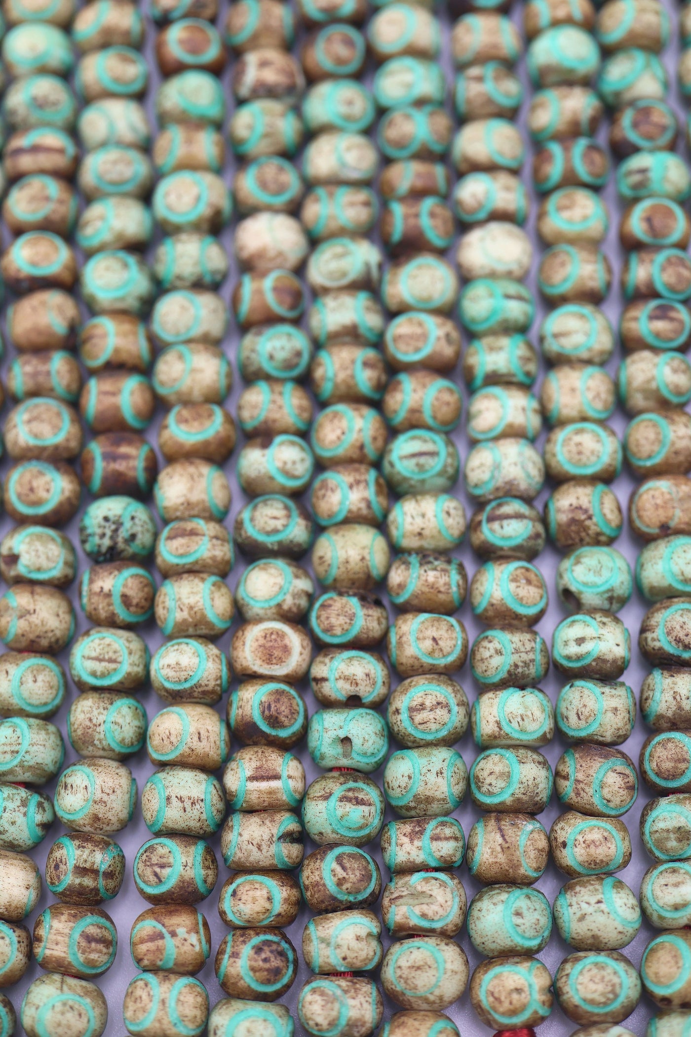 Close-up of rustic brown bone beads with turquoise circle patterns on strand