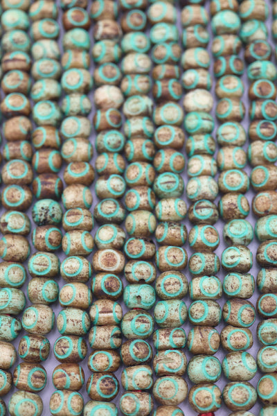 Close-up of rustic brown bone beads with turquoise circle patterns on strand