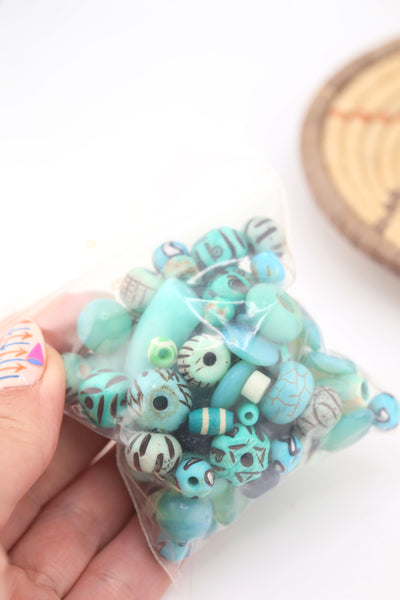 Clear bag filled with turquoise grab bag beads, showing a colorful assortment of artisan-style beads in blue-green tones.